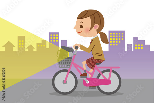 ライトを点灯し自転車を運転する女子生徒(背景あり)