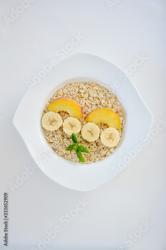 Fresh oatmeal porridge with banana, peach and honey for healthy breakfast