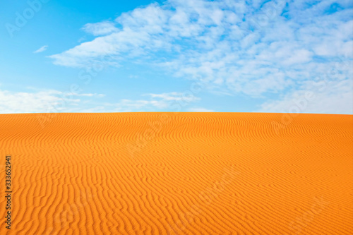 Bright orange color rippled desert sand and clear blue sky for a hot summer background. Arabian desert, Riyadh, Saudi Arabia