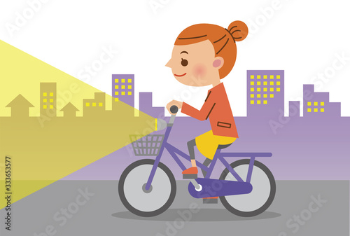 夜間ライトを点灯し自転車を運転する女性(背景あり)