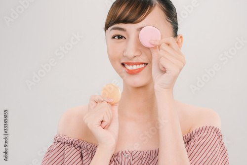 Portrait of a beautiful young woman wearing pink dress standing isolated over pink background, holding macaroons