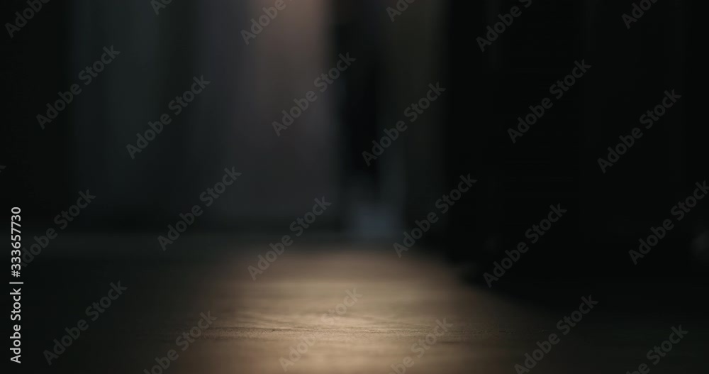 Slow motion closeup of man walking on concrete floor with bare foot in dark room