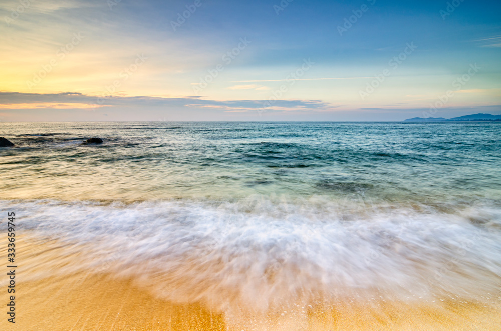 Beautiful morning background on the beach. Soft wave hitting the coastline and cloudy sky