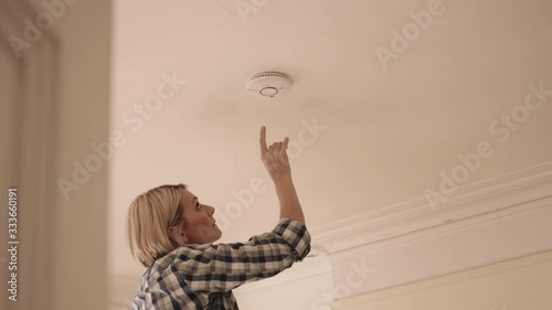 Adult Woman installing smoke detector in home photo