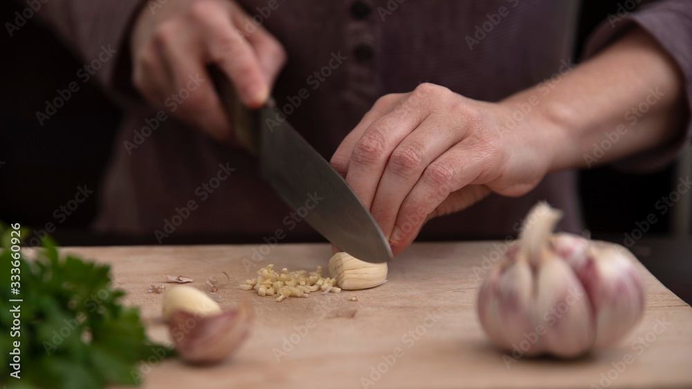 Close-up of the hands of a person cutting garlic with a knife