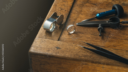 Jewelry craftsmanship desk. The jeweller engraver tools and golden diamonds ring photo