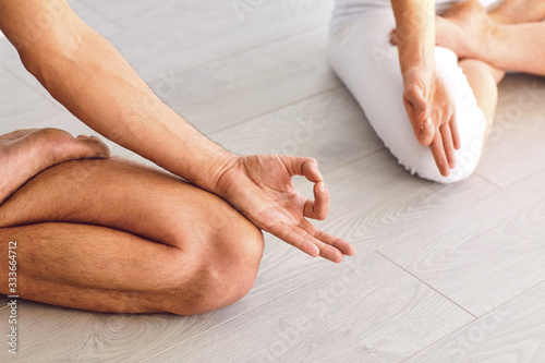 Close up of yoga couple people hand sitting relaxation in lotus field on floor in studio class.