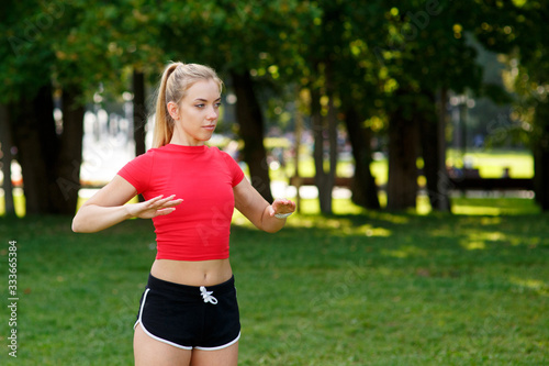 A young blonde girl is engaged in sports in the park, a woman does a warm-up in the street. Active outdoor training