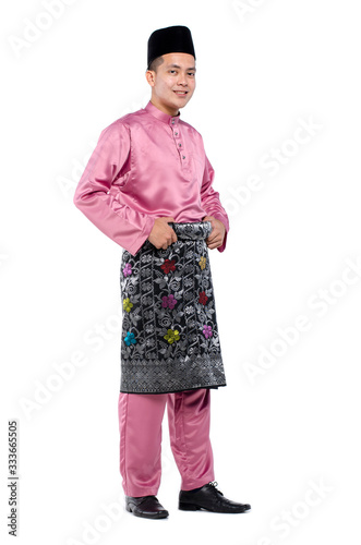 Portrait of young muslim with malaysian traditional attire called baju melayu standing against white background photo