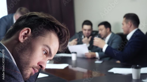 Thoughtful indifferent concentrated ceo boss experiencing anxiety, feel doubt during discussion of businesspeople coworkers indoor. Uncertain concern challenge, strategy dilemma of worried tense chief