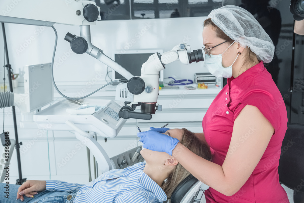 The dentist doctor looks in a microscope at the patient teeth. The concept of health care and treatment in medical facilities The dentist doctor looks in a microscope at the patient teeth. The concept of health care and treatment in medical facilities