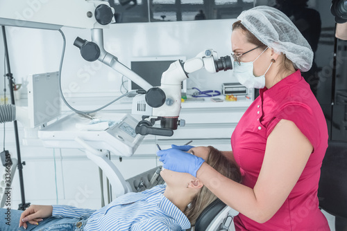 The dentist doctor looks in a microscope at the patient teeth. The concept of health care and treatment in medical facilities