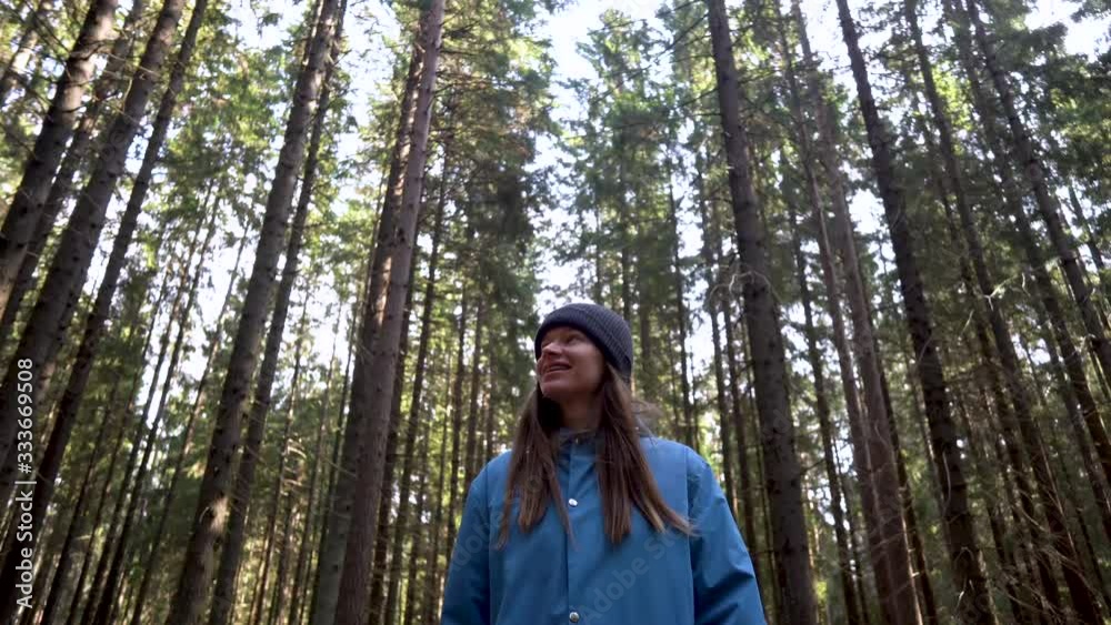 Portrait of a Young Beautiful Woman in a Romantic Nature Atmosphere. Girl is Dressed in Pantone Classic Blue Raincoat and is Walking on the Forest . She Smiles and Walks in the Woods Alone. Portrait of a Young Beautiful Woman in a Romantic Nature Atmosphere. Girl is Dressed in Pantone Classic Blue Raincoat and is Walking on the Forest . She Smiles and Walks in the Woods Alone.