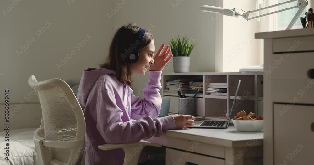Teenage girl school student wearing wireless headphones conference calling on laptop distance learning at home. Teen schoolgirl chatting by web cam preparing for test or exam with online teacher.