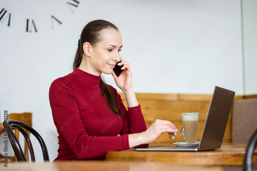 Young woman works and speaks on the phone with laptop and a coffee at home Young woman works and speaks on the phone with laptop and a coffee at home
