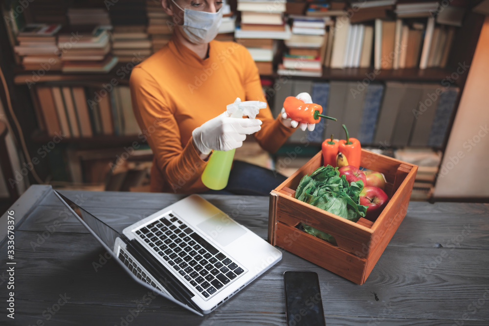 Woman with protective medical mask spraying sterilizing chemical on the food ordered from internet delivery. Woman with protective medical mask spraying sterilizing chemical on the food ordered from internet delivery.