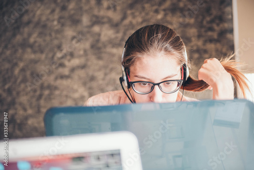 Young woman in headphones speaking looking at laptop. Work from home. Online work. photo