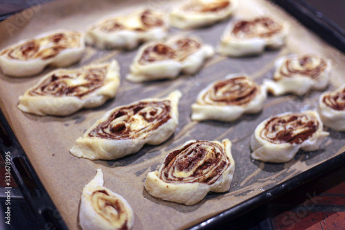 sweet rolls with cinnamon on the tray - backery or cooking at home. A detail of raw cinnamon buns - very shallow depth of field. photo