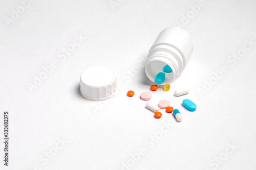 White plastic bottle with medicines and vitamines. tematic health. rose, orange and blue medicines. photo