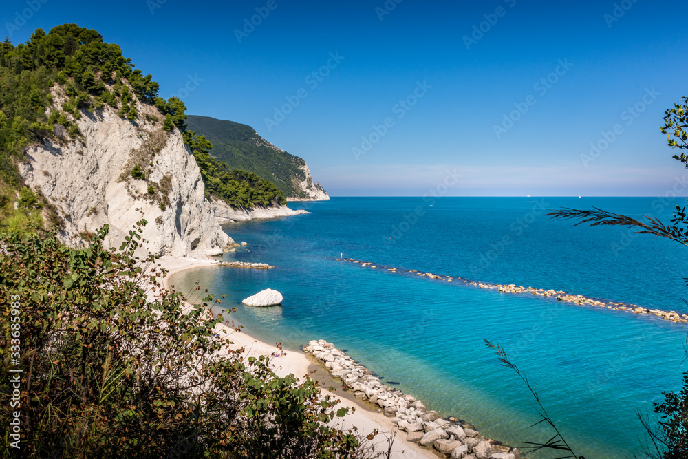 Beach of Numana Alta, with the white cliffs and clear blue water of the adriatic in Summer