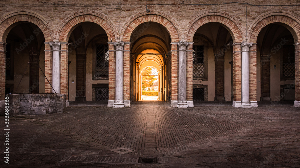 Arches of Palace Venieri with golden hour sunlight shining in through the entrance doorway, Recanati, Italy