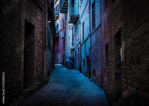 An atmospheric, narrow, back alley painted with blue and magenta light taken in Recanati, Macerata, Italy