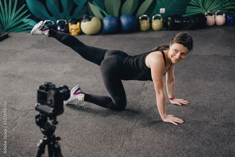 Young female fitness instructor making online training. Young fitness instructor shows how to exercise at home.