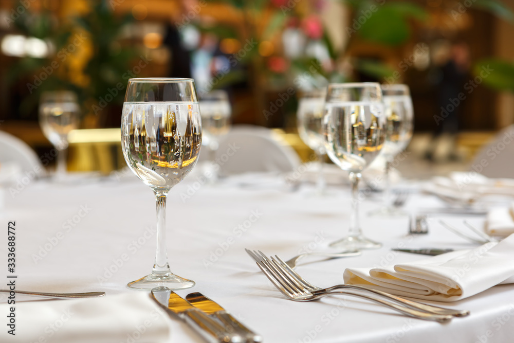 Empty glasses and white napkins are installed in the restaurant on the table.