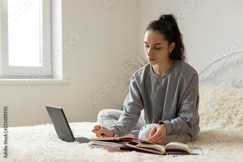 Young girl woman on the bed, distance learning for students. Coronavirus. Quarantine. Woman look at a laptop computer. Freelancer, distant work, work at home, online education