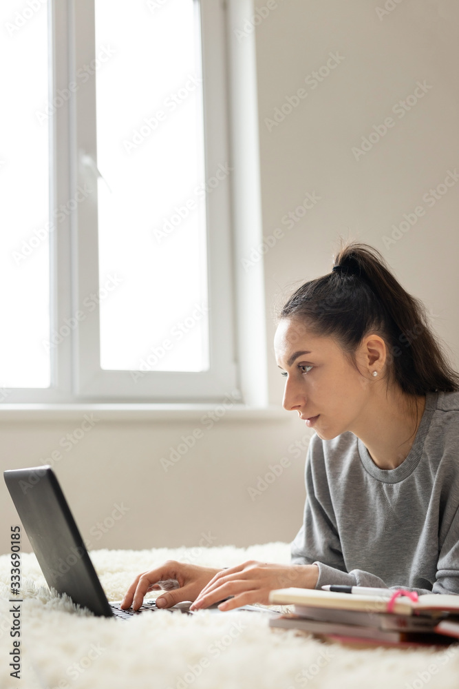 Young girl woman on the bed, distance learning for students. Coronavirus. Quarantine. Woman look at a laptop computer. Freelancer, distant work, work at home, online education Young girl woman on the bed, distance learning for students. Coronavirus. Quarantine. Woman look at a laptop computer. Freelancer, distant work, work at home, online education