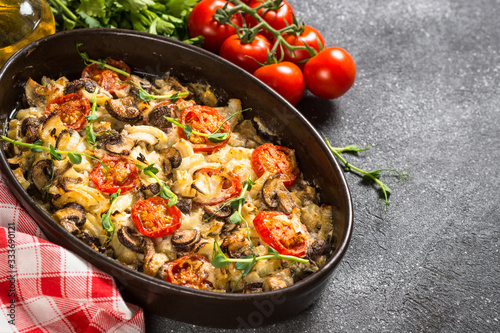 Baked meat with vegetables on black table.