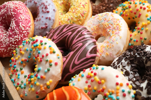 Fotografie Yummy glazed donuts with sprinkles, closeup view
