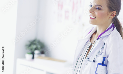 Smiling female doctor with a medical stethoscope in uniform standing