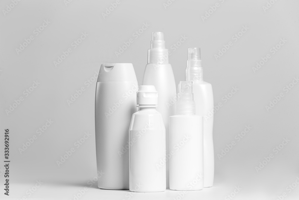 Set of cosmetic products in white and grey containers on light background.