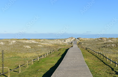 Beach with wooden boardwalk and sand dunes with grass and blue sky. Arteixo  Coru  a  Galicia  Spain.