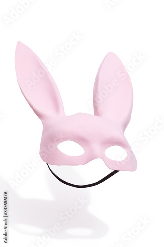 Subject shot of a pink velvet bunny mask with long ears with a black elastic strap for easy wear. The mask for costume party is isolated on the white background.
