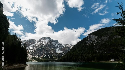 The lake shaded by clouds is illuminated by the light of the filtering sun, while in the background tourists come to visit a small church