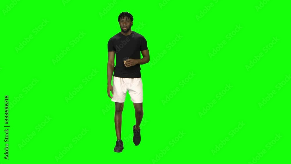 African american man is walking and drinking coffee at Green Screen, Chroma Key. Front view. African american man is walking and drinking coffee at Green Screen, Chroma Key. Front view.