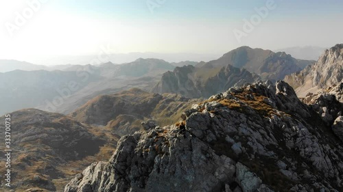 Aerial panoram view of girl rises on a mountain ridge. Beautiful view of the peaked tops of Durmitor in Montenegro