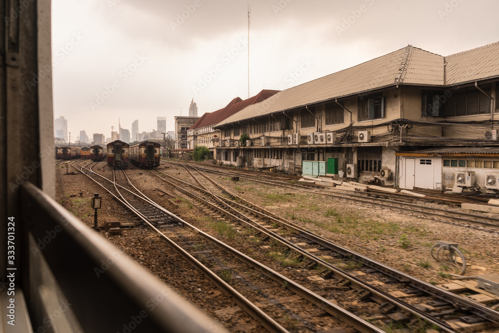 Trains on a hazy day in central train station. Skyscrapers in distance. Arrival from Don Mueang International Airport