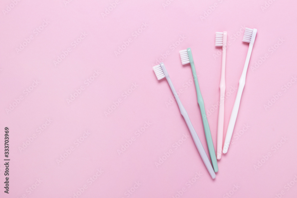 Pink, green, white and gray toothbrushes on pink background. Taking care of teeth, dental concept. Flat lay photo, copy space, top view. Pink, green, white and gray toothbrushes on pink background. Taking care of teeth, dental concept. Flat lay photo, copy space, top view.
