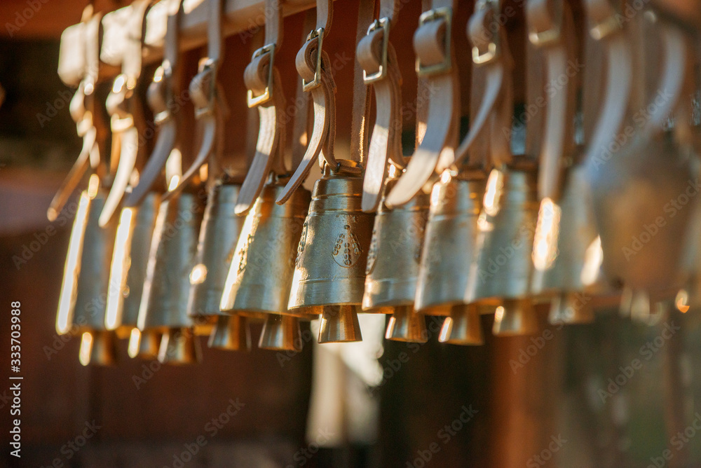 Bells neatly arranged in a row, gently rocking in the breeze, beautiful warm light. Golden colour pallet. 