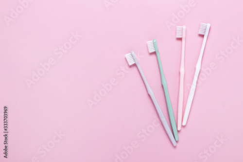 Pink, green, white and gray toothbrushes on pink background. Taking care of teeth, dental concept. Flat lay photo, copy space, top view.