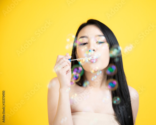 Wallpaper Mural portrait asian woman smile face Blowing Bubbles  with yellow background Torontodigital.ca