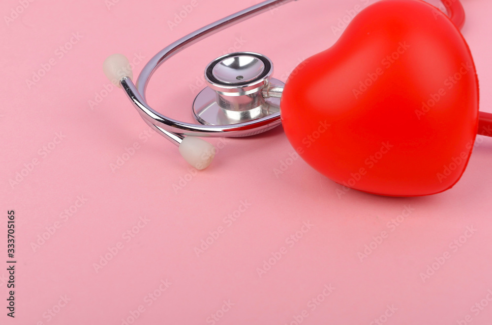 Red heart with stethoscope on pink background. Heart health care concept. Selective focus. Red heart with stethoscope on pink background. Heart health care concept. Selective focus.