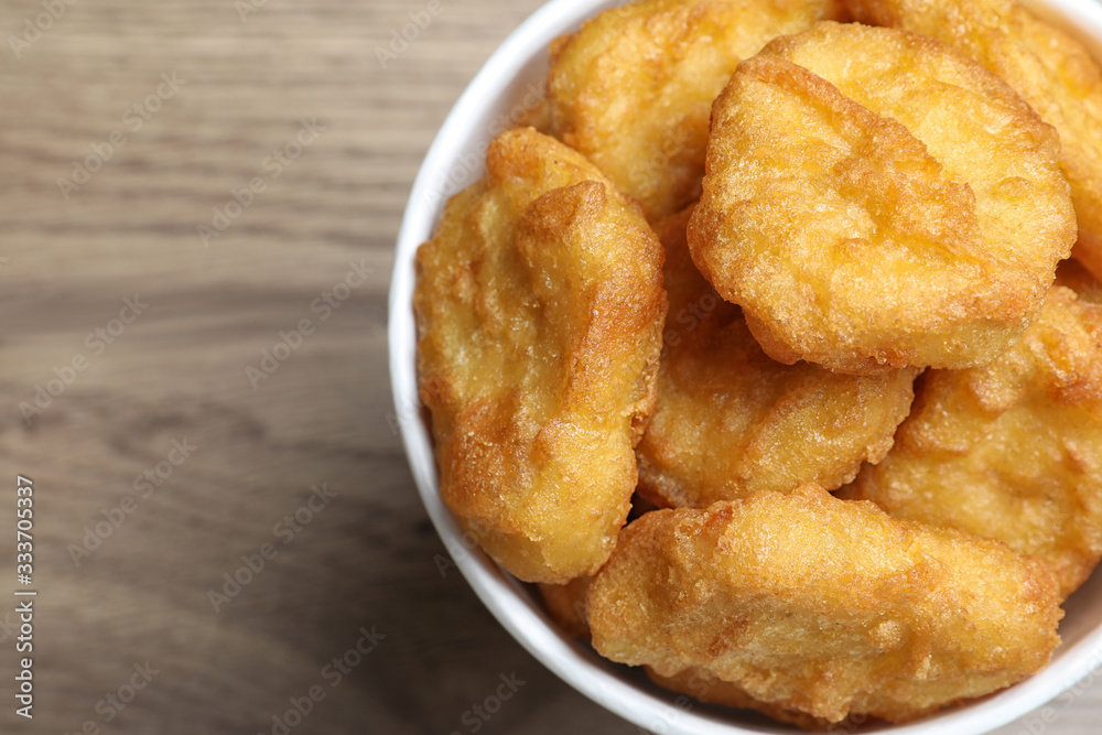 Bucket with tasty chicken nuggets on wooden table, top view Bucket with tasty chicken nuggets on wooden table, top view