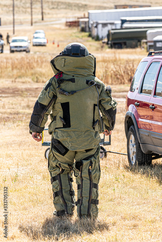 An EOD Bomb Technician with a full bomb suit walks up to a vehicle to search it