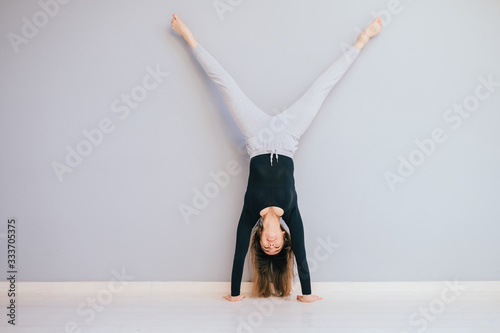 Fotografija Fit woman doing handstand near wall