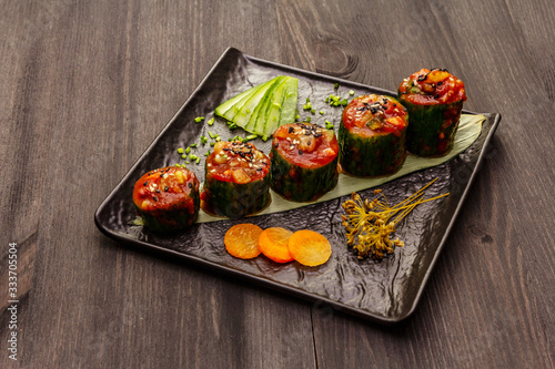 Korean style stuffed cucumbers. Kojori kimchi spicy snack. Fermented and marinated vegetables. Wooden background photo