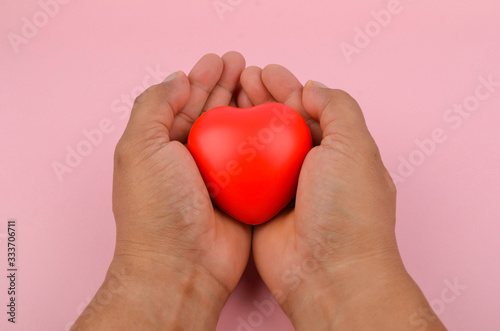 Fototapeta Naklejka Na Ścianę i Meble -  Health concept. Hand holding red heart on pink background. Selective focus.